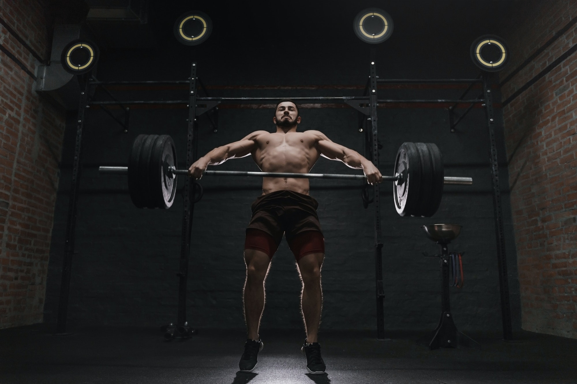 Young crossfit athlete lifting heavy barbell at the gym